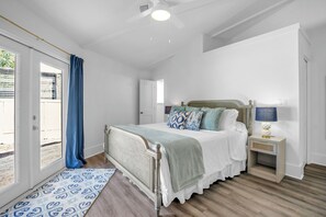 Un dormitorio con cama, mesita de noche, lámpara y vistas al exterior.