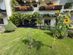 Un patio con zona de comedor, plantas en macetas y césped bien cuidado.