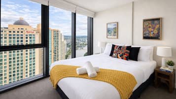 A hotel room with a large bed, a view of the cityscape, and a Marriott hotel building in the background.