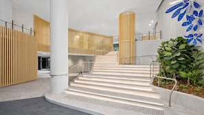 A modern interior with a central staircase, white walls, and a decorative blue leaf pattern on the wall. - Sky-high Haven-rooftop Infinity Pool Parking Wifi (Brisbane)