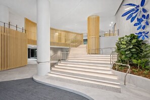 A modern interior with a central staircase, white walls, and a decorative blue leaf pattern on the wall. - Sky-high Haven-rooftop Infinity Pool Parking Wifi (Brisbane)