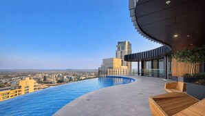 A rooftop infinity pool with a city view, modern architecture, and wooden seating areas. - Sky-high Haven-rooftop Infinity Pool Parking Wifi (Brisbane)