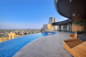 A rooftop infinity pool with a city view, modern architecture, and wooden seating areas. - Sky-high Haven-rooftop Infinity Pool Parking Wifi (Brisbane)