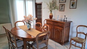 Ein Essbereich mit Holztisch, Stühlen, einer Blumenvase, einem Schrank und Wandbildern.