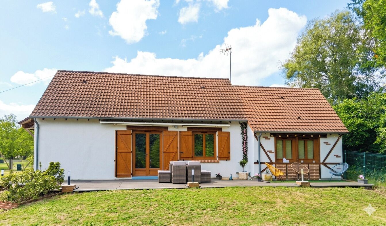 A single-story house with a tiled roof, a front porch with outdoor furniture, and a small garden area.