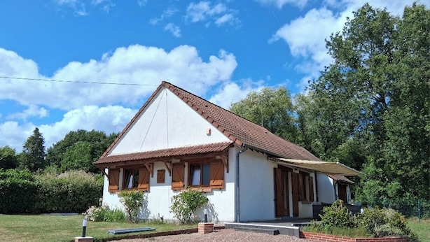 Ein eingeschossiges Haus mit Satteldach, einer Veranda und einem kleinen Garten.