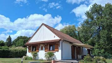 A single-story house with a pitched roof, a front porch, and a small garden area.