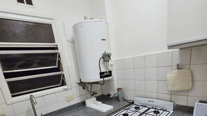 A compact kitchen with a sink, stove, and a water heater. - Comfortable and Well-Located in Recoleta (Buenos Aires)