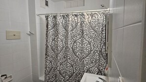 A bathroom with a toilet, sink, and shower curtain. - Comfortable and Well-Located in Recoleta (Buenos Aires)