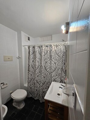Een badkamer met toilet, wastafel en douchegordijn.