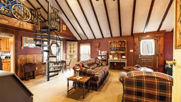 A cozy living room with a staircase, a sofa set, and a dining area.