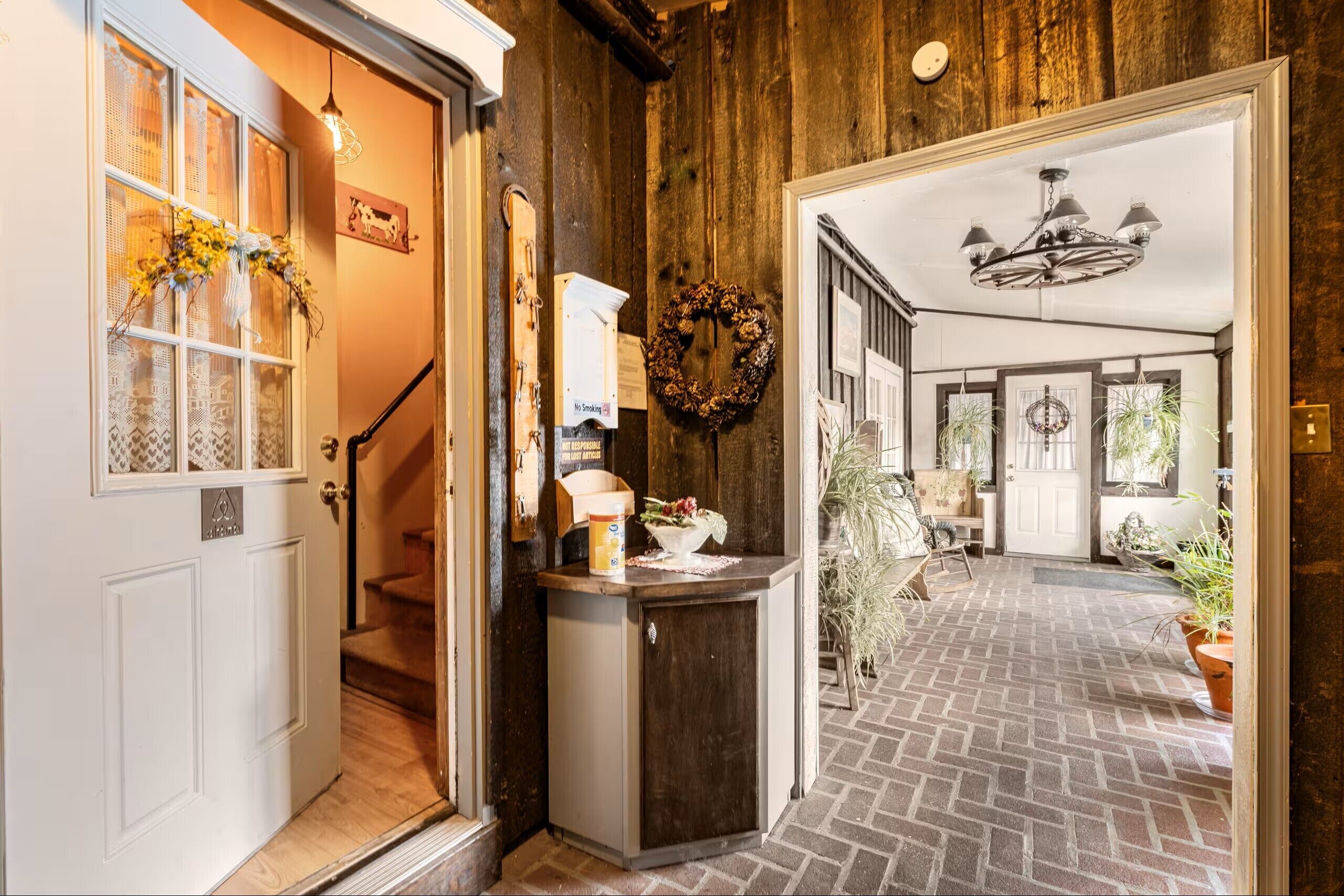 A hallway with a wooden floor, a white door, and a staircase leading to another room.
