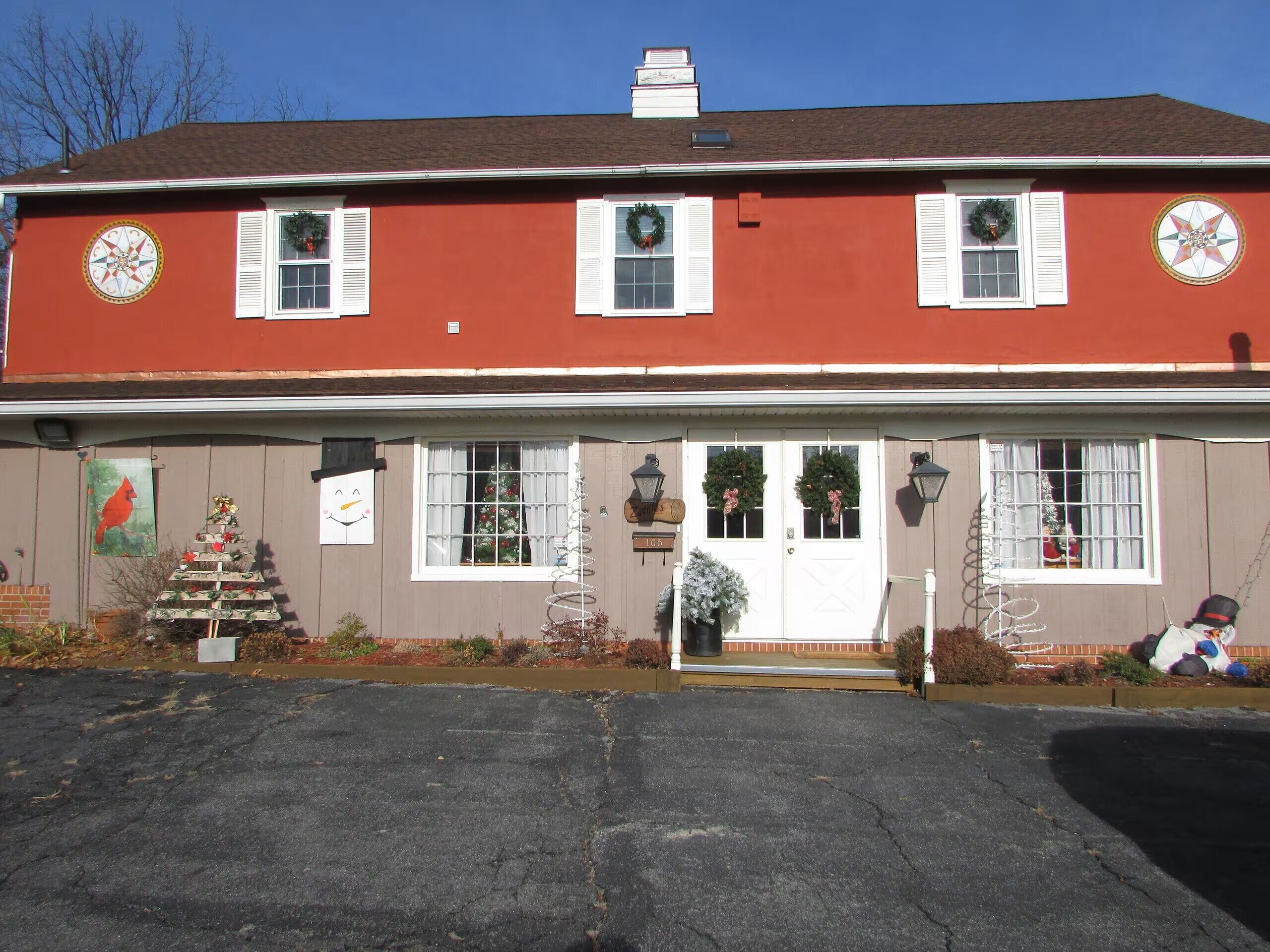 A two-story building with a red facade, white shutters, and a front porch.