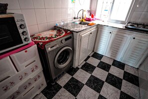A kitchen with a washing machine, a microwave, and a sink. - Charming 2-bedroom Apartment With Direct sea View in Martil (Martil)