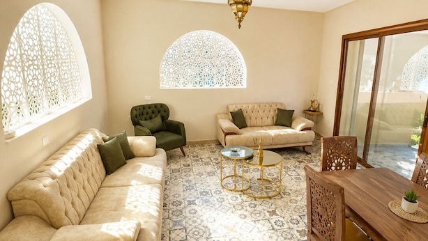 A living room with a beige sofa, a green armchair, a patterned floor, and a dining table with chairs. - 2-bedroom apartment in charming Menzel Jemil with AC (Menzel Jemil)