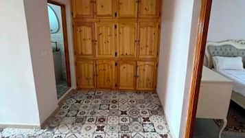 A room with a patterned tile floor, a wooden wardrobe, and a hanging light fixture.