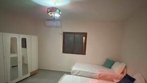 A bedroom with a bed, a wardrobe, a window, and a ceiling light fixture. - 2-bedroom apartment in charming Menzel Jemil with AC (Menzel Jemil)