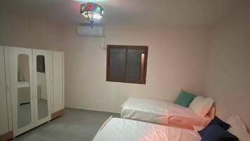 A bedroom with a bed, a wardrobe, a window, and a ceiling light fixture.