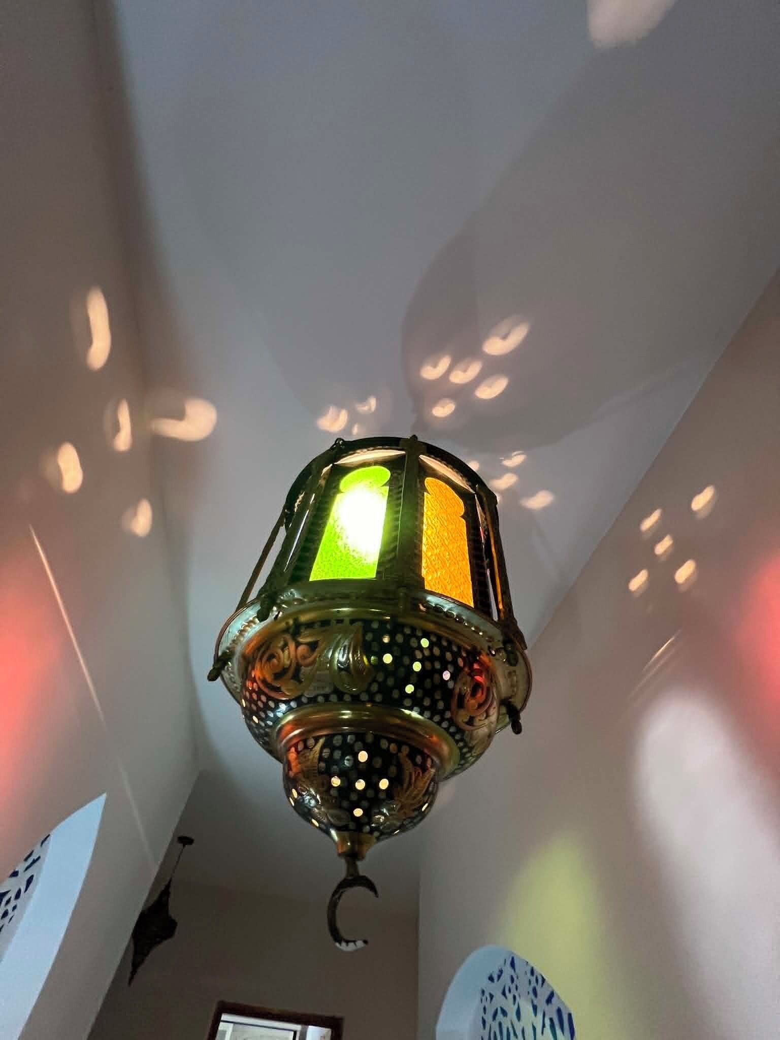 A hanging lantern with a green glass shade and decorative metalwork.