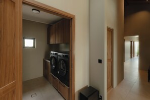 A laundry room with two front-loading washing machines, wooden cabinets, and a small window. - Mountain Villa II. Fantastic 5-bedroom house, perfect for families (Hrunamannahreppur)