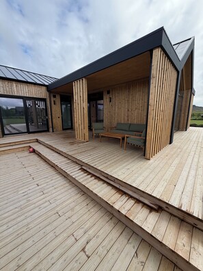 A modern wooden deck with a built-in seating area and a view of the landscape. - Mountain Villa II. Fantastic 5-bedroom house, perfect for families (Hrunamannahreppur)