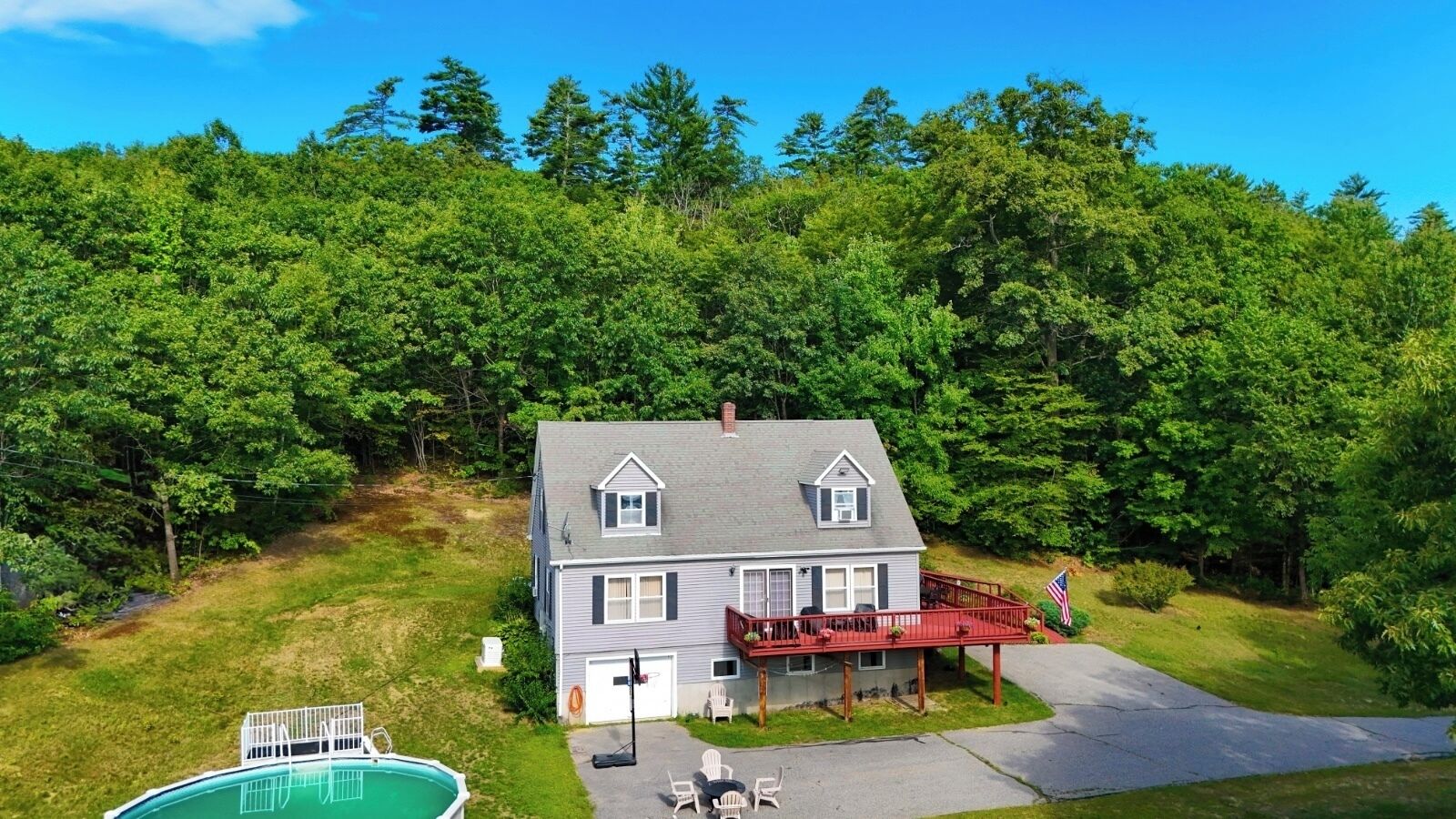 Une maison à deux étages avec une terrasse à l’avant, une piscine et un drapeau.
