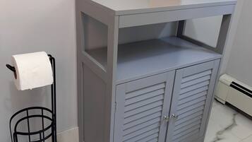 A bathroom with a grey vanity, a toilet paper holder, and a tissue box.
