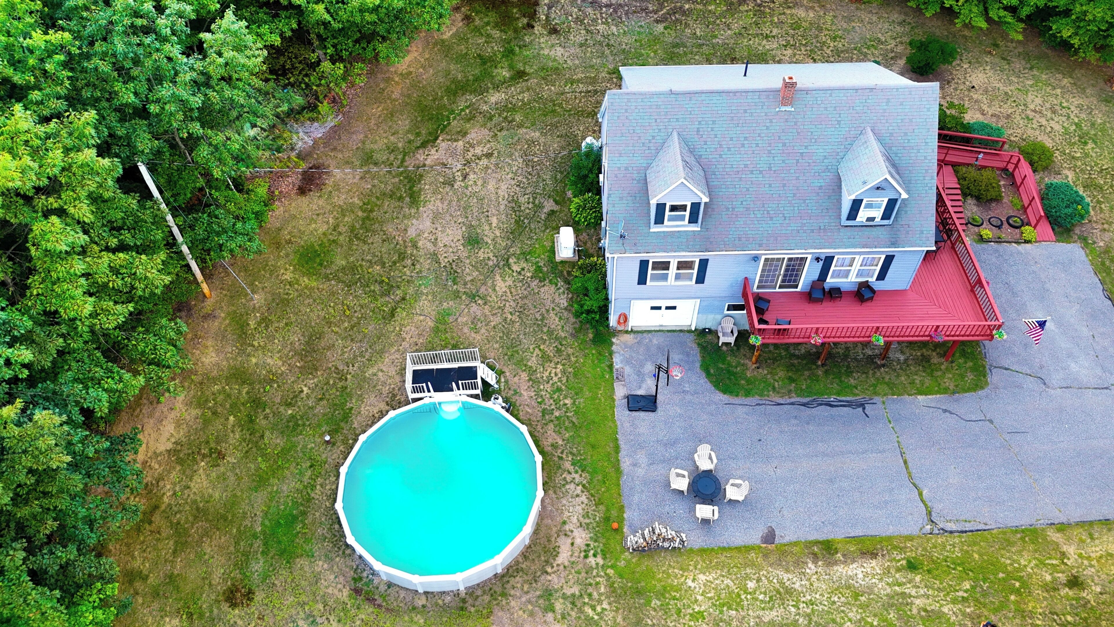 A two-story house with a swimming pool, a red deck, and a flag.