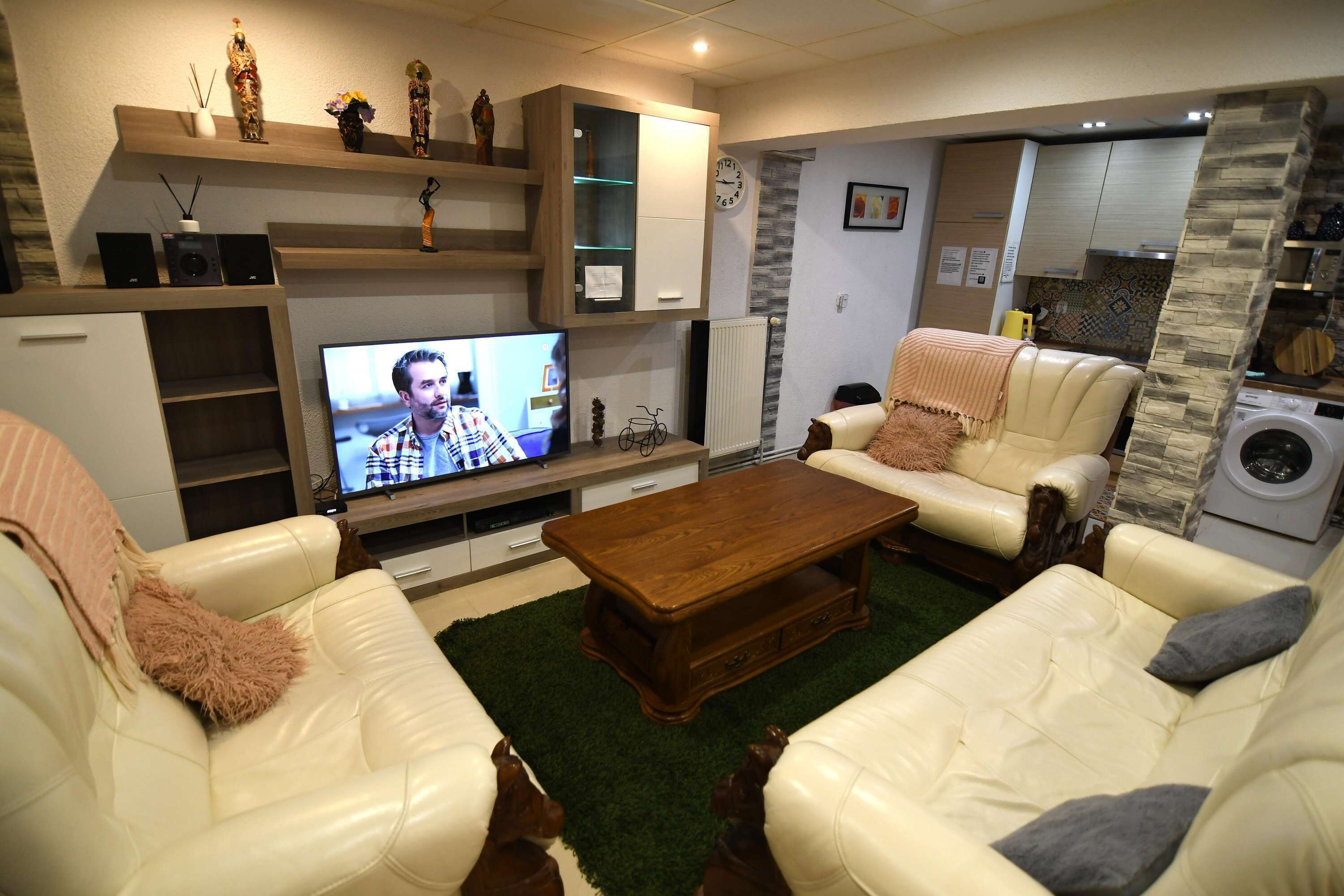 Una sala de estar con televisor, sofás, una mesita de centro y una pared de acento de piedra.