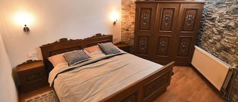 Un dormitorio con cama de madera, pared de piedra y un armario.