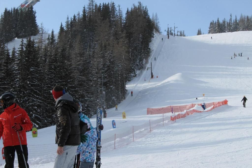 A snowy ski slope with skiers and a snowboarder.