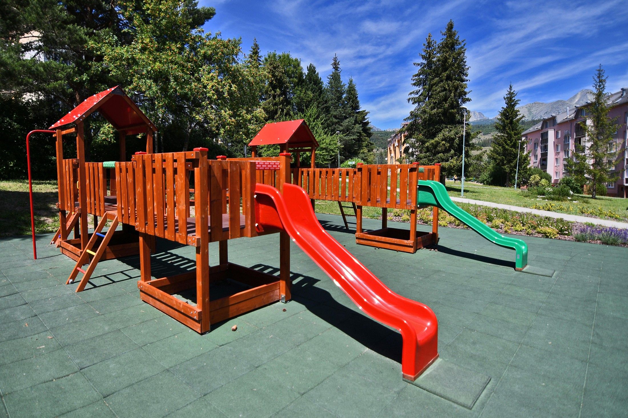 A playground with a wooden climbing structure and slides.