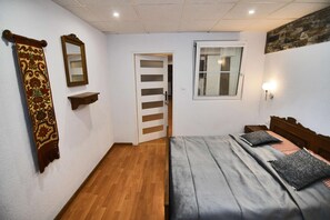 Ein Schlafzimmer mit einem Bett, einem Nachttisch, einem Spiegel, einem Fenster und einer Tür.