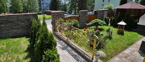 A residential area with a paved pathway, stone walls, and a decorative metal fence.