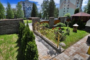 Una zona residenziale con un vialetto lastricato, muri in pietra e un cancello decorativo in metallo.