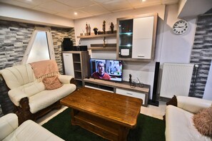 Ein Wohnzimmer mit einer Couch, einem Couchtisch, einem Fernseher und Dekorationselementen.