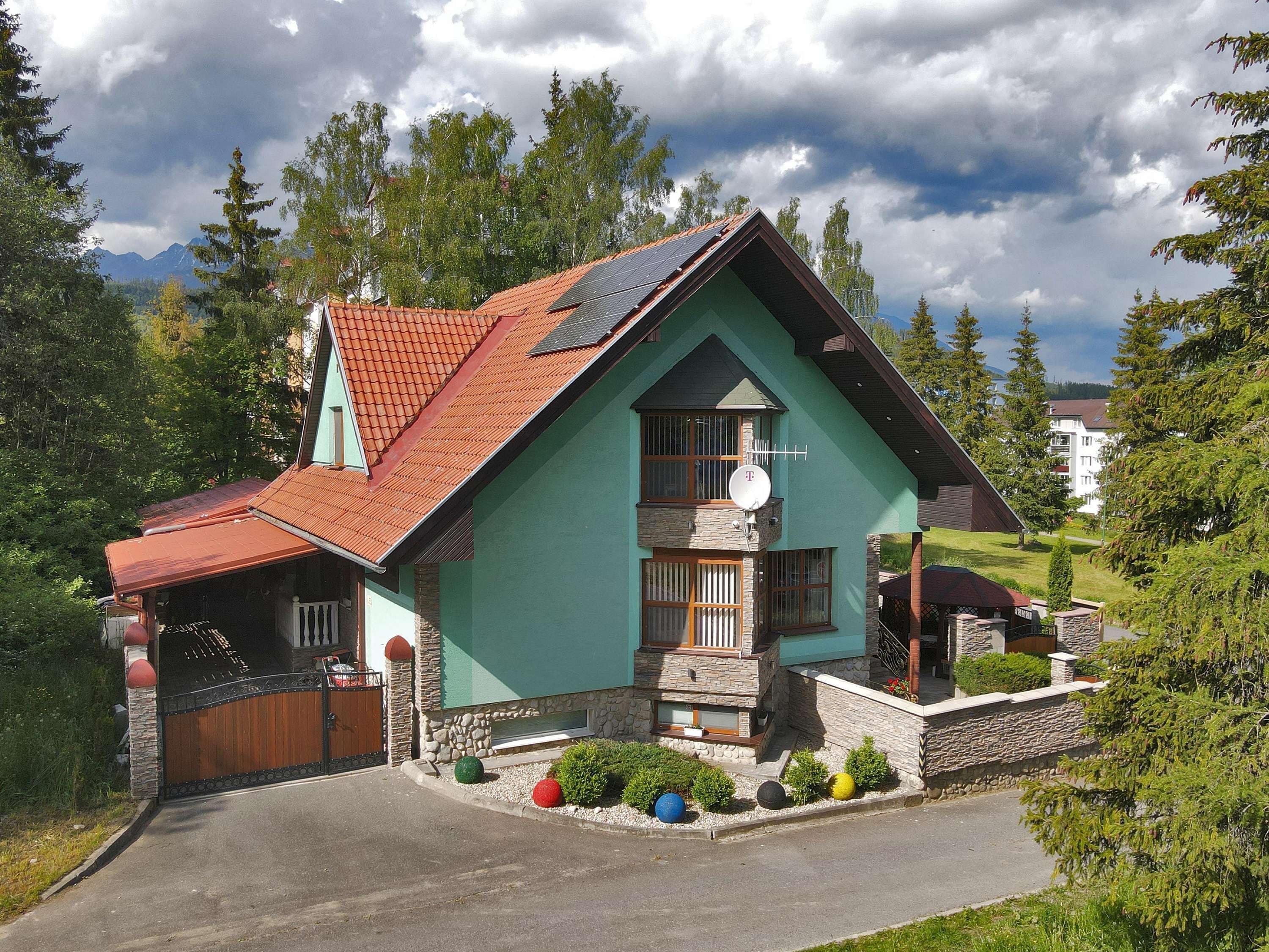 Una casa con techo inclinado, antena parabólica y base de piedra.