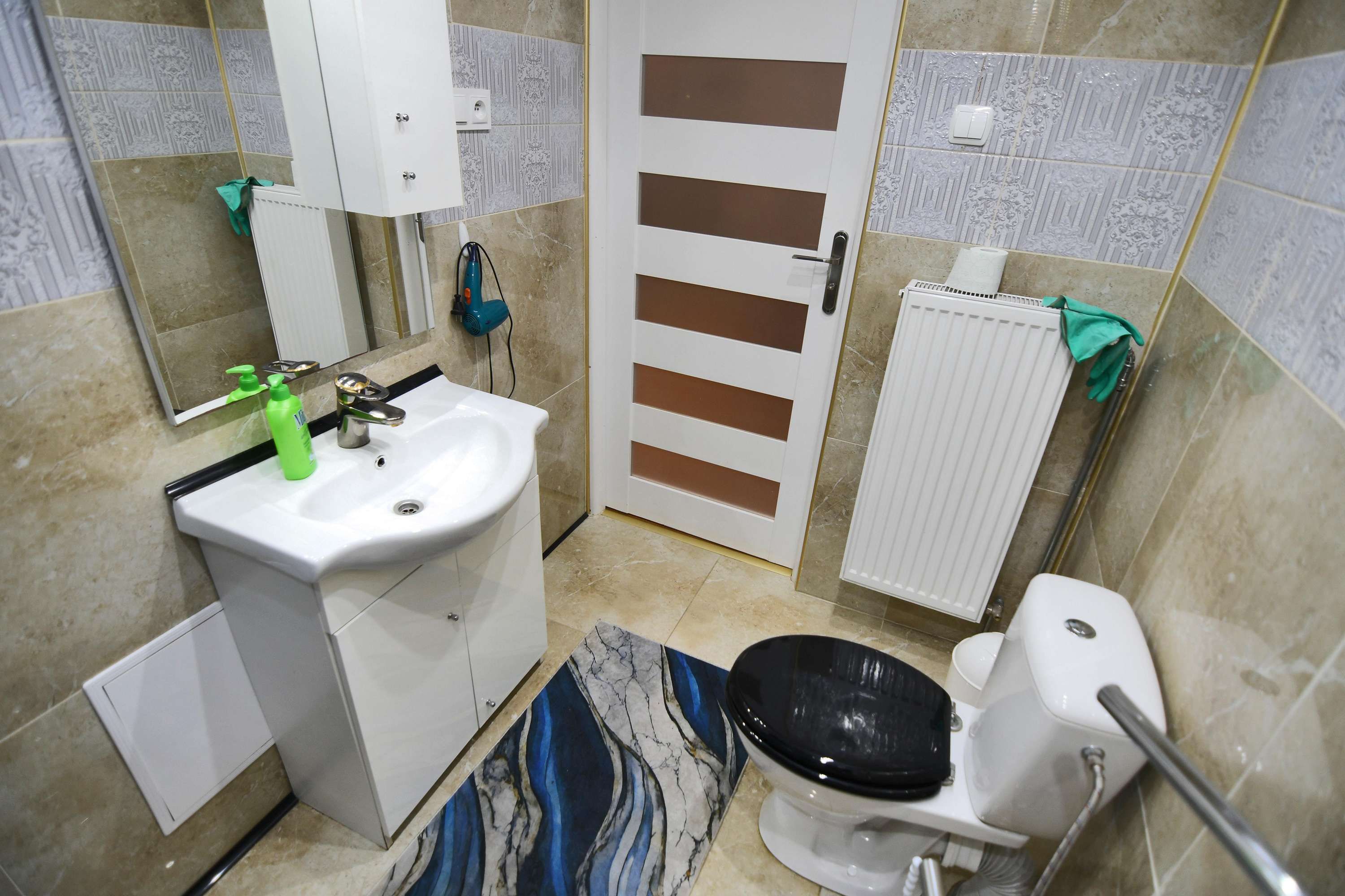 Un baño con un lavamanos blanco, un inodoro, un perchero y una puerta con una toalla colgada.