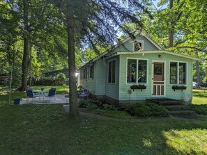 A small, single-story house with a porch, surrounded by trees and a grassy yard. - Cozy 1-bedroom/ 1 loft cottage in serene Lakeview- sleeps 8 (Lakeview)
