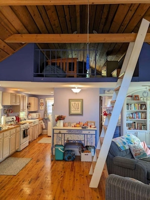 Un loft espaiós amb cuina, zona de dinar i un racó d'estar acollidor amb una escala.