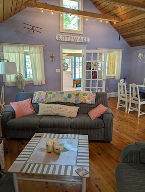 A cozy room with a couch, a table with candles, and a sign that reads 'KITTYWAKE'. - Cozy 1-bedroom/ 1 loft cottage in serene Lakeview- sleeps 8 (Lakeview)