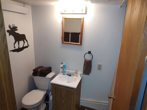 Un bagno con il water, un lavandino, uno specchio e un adesivo murale raffigurante un alce.