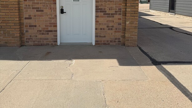 A building with a white door, brick walls, and a metal awning.