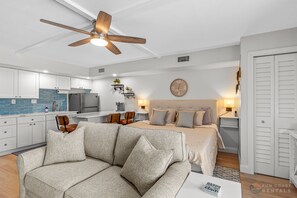 Ein modernes, helles Schlafzimmer mit Bett, Nachttisch und Wanduhr.