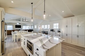 A spacious kitchen with a large island, white cabinetry, and a modern chandelier. - Beach in Your Backyard! Seaside Strathmere Estate (Strathmere)