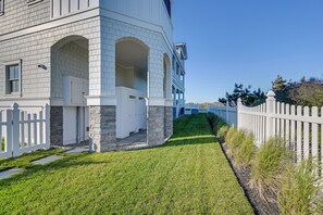 Ein zweigeschossiges Haus mit weißer Fassade, Steinverzierungen und einem weißen Zaun.