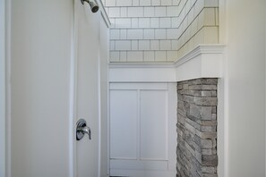 A bathroom with a white door, a shower area, and a stone accent wall. - Beach in Your Backyard! Seaside Strathmere Estate (Strathmere)