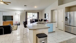 A modern kitchen with a central island, stainless steel appliances, and a dining area with chairs and a table. - Private Pool & Spa: North Las Vegas Retreat! (North Las Vegas)