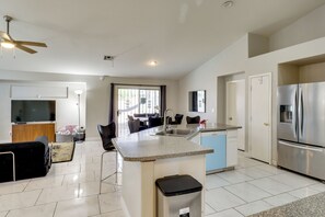 Een moderne keuken met een centraal eiland, roestvrijstalen apparatuur en een eethoek met stoelen en een tafel.