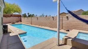Une piscine avec une terrasse en bois et un mur de briques en arrière-plan.